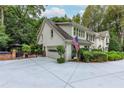 Charming home featuring a manicured yard, attached garage, and brick patio area with outdoor seating at 8480 Valemont Dr, Sandy Springs, GA 30350