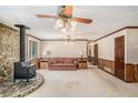 Cozy living room featuring a stone fireplace, wood paneling, and vintage ceiling fans at 95 Oak Grove Cir, Mcdonough, GA 30253