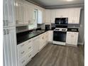 Bright kitchen featuring white cabinets, black countertops, stainless appliances, and vinyl floors at 6471 Ansley Blvd, Lithia Springs, GA 30122