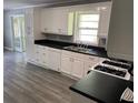 Renovated kitchen boasts white cabinetry, black countertops and modern vinyl flooring at 6471 Ansley Blvd, Lithia Springs, GA 30122