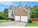 Beautiful shot of the home's front exterior, highlighting the two-car garage, manicured lawn and mature trees at 157 Spur Ln, Hiram, GA 30141