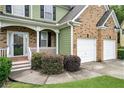 Close up view of the home featuring a covered entry, two-car garage, and manicured shrubbery at 157 Spur Ln, Hiram, GA 30141