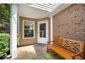 Inviting covered front porch featuring a wooden bench, brick accents, and a view of the landscaped yard at 1901 Brittania Cir, Woodstock, GA 30188