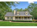 Beautiful home with a covered front porch and manicured lawn, set against a backdrop of mature trees at 1420 Pilgrim Rd, Cumming, GA 30040