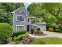 Two-story gray home featuring mature trees, lush landscaping, and a well-manicured lawn at 115 Township Ct, Woodstock, GA 30189