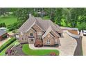Aerial view of a brick home with an attached garage and a spacious driveway, surrounded by lush landscaping at 5009 Kingsley Manor Ct, Marietta, GA 30066