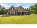 Traditional two-story home boasts a brick facade, a covered front porch, and lush green landscaping at 739 E Mays E Rd, Stockbridge, GA 30281