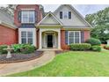 Inviting front entrance of a brick home with a manicured lawn and pathway to the front door at 5036 Weatherstone Drive, Buford, GA 30519