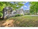 Gray home with an attached garage, bright yellow front door, landscaped front yard, and surrounded by mature trees and greenery at 2730 Samples Rd, Cumming, GA 30041