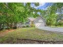 Charming one-story home with a gray exterior, attached garage, manicured lawn, and bright yellow front door, surrounded by trees at 2730 Samples Rd, Cumming, GA 30041