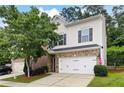 Two-story home with white siding, an attached garage, brick accents and a well-manicured front lawn at 403 Village Vw, Woodstock, GA 30188