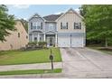 Two-story home with a well-kept lawn, double garage, and charming architectural details at 7530 Springbox Dr, Fairburn, GA 30213