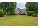 Expansive front lawn with mature trees framing a beautiful stone house with striking curb appeal at 165 Ansley Way, Roswell, GA 30075