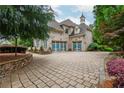 Three-car garage with charming carriage doors and a stone paver driveway, framed by lush landscaping at 165 Ansley Way, Roswell, GA 30075