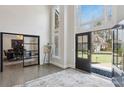 Open front door with glass sidelights leads to hardwood foyer with an office behind glass doors at 1460 Lakemist Ct, Roswell, GA 30075