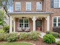 Inviting front porch with seating area, beautiful landscaping, and a classic red front door at 508 Highland Dr, Woodstock, GA 30188