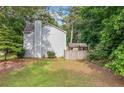Large backyard featuring green grass, mature trees, a wooden fence, and storage building at 802 Bluff Pl, Woodstock, GA 30188