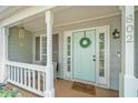 Inviting front porch featuring a teal door with a wreath, sidelights, and a 'yay! you're here!' welcome mat at 802 Bluff Pl, Woodstock, GA 30188