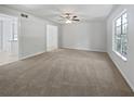 Spacious, well-lit living room with neutral carpet, a ceiling fan, and a large window, providing a blank canvas at 978 Monopoly Dr, Lawrenceville, GA 30046