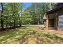 Expansive side yard with green grass leading to mature hardwood trees, plus view of covered porch at 1687 Harmony Rd, Temple, GA 30179