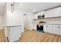 Bright open kitchen featuring white cabinets, stainless steel appliances, modern backsplash, and hardwood floors at 383 Oakridge Dr, Cartersville, GA 30121