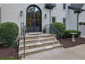 Stunning stone steps lead to an elegant arched front door with wrought iron detailing and tasteful landscaping at 525 Old Path Xing, Roswell, GA 30075