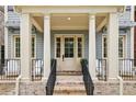 Inviting front porch with white columns, brick steps, black railing, and seating area at 105 Cumming St, Alpharetta, GA 30009