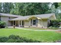 Landscaped front yard of a charming house with large lawn and mature trees in a serene, wooded setting at 4140 Candler Lake West Ne, Atlanta, GA 30319