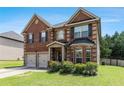 Inviting two-story brick home with a two-car garage, a well-kept lawn, and a welcoming front entrance at 10044 Cormac St, Jonesboro, GA 30238