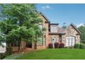 Two-story brick home with stone accents, manicured lawn, and mature shade tree at 3410 Enclave Mill Ct, Dacula, GA 30019