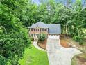 Aerial view of a brick home, showcasing its manicured lawn and tree-lined surroundings at 135 Crimson Rdg, Tyrone, GA 30290