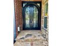 Elegant black arched double doors with decorative ironwork and stone steps, adding a touch of sophistication to the entrance at 3499 Lake Mill Rd, Buford, GA 30519