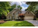 Charming home with a well manicured lawn, colorful shrubbery, and a two-car attached garage at 9975 Groomsbridge Rd, Johns Creek, GA 30022