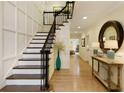 Spacious foyer with hardwood floors, a staircase with wrought iron railings, and a decorative mirror at 9975 Groomsbridge Rd, Johns Creek, GA 30022