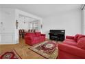 Bright living room features red sofas, a piano, and decorative rugs over hardwood flooring, creating an inviting space at 7027 Walham Grv, Duluth, GA 30097
