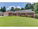 Charming brick home featuring a well-maintained lawn and colorful landscaping, complemented by black shutters at 3550 Miller Farms Ln, Peachtree Corners, GA 30096