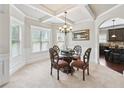 Elegant dining area with a chandelier, coffered ceiling, and direct access to the kitchen area at 3024 Bridgehaven Ct, Snellville, GA 30039