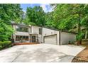 Stylish two-story home showcasing a spacious driveway and a two-car garage complemented by lush trees in the background at 4290 Inverness Ne Ct, Roswell, GA 30075