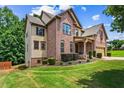 Spacious two-story home featuring a brick facade, lush lawn, and mature trees at 6175 Beaver Crossing Dr, Cumming, GA 30040