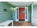 Welcoming front porch with a red door, white trim, and a bench at 1920 Daves Creek Trl, Cumming, GA 30041