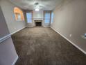 Spacious living room with a cozy fireplace, neutral carpet, and ample natural light from the windows at 2527 Plymouth Way, Conyers, GA 30013