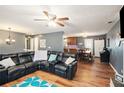 Open-concept living room featuring a cozy black sectional couch, hardwood floors, and modern ceiling fan at 6355 Queens Rd, Douglasville, GA 30135