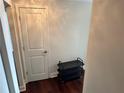 Neutral colored walls and dark hardwood flooring lead to a white door and a black metal shoe rack at 2479 Peachtree Ne Rd # 1714, Atlanta, GA 30305