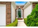 Inviting entryway with a green front door framed by brick and decorative shrubs at 910 Laurel Cove Dr, Snellville, GA 30078