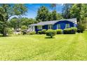 Charming blue home featuring a lush green lawn, mature trees, and manicured shrubs at 2011 Lexington Ave, Atlanta, GA 30344