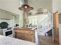 Open kitchen with butcher block island, stone fireplace, and staircase at 10540 Serenbe Ln, Chattahoochee Hills, GA 30268
