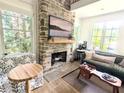 Cozy living room with a stone fireplace and lots of natural light at 10540 Serenbe Ln, Chattahoochee Hills, GA 30268