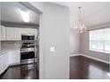 Dining area with dark wood floors, a chandelier, and a view into the kitchen with its stainless-steel appliances at 5414 Sweetsprings Sw Dr, Powder Springs, GA 30127