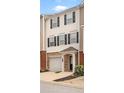 View of townhome featuring brick accents, attached garage, black shutters, and covered entry at 920 Society Sw Cir, Atlanta, GA 30331