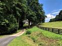 Scenic driveway view of a charming home nestled amongst mature trees and lush landscaping at 1580 Lower Burris Rd, Canton, GA 30114